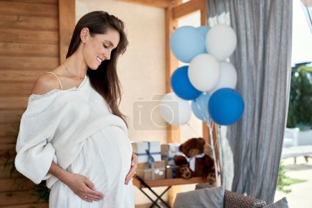 Téléchargez les photos : Femme enceinte souriante avec des décorations bleues à l'extérieur - en image libre de droit