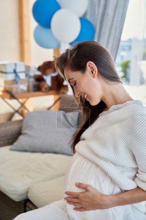 Téléchargez les photos : Smiling caucasian pregnant sitting at the sofa outdoors - en image libre de droit