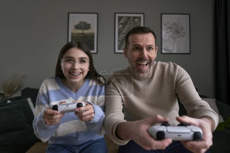 Téléchargez les photos : Adolescent caucasien fille avec papa jouer à jeu vidéo - en image libre de droit