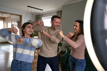 Photo for Teenager girl with parents recording dancing  for social media - Royalty Free Image