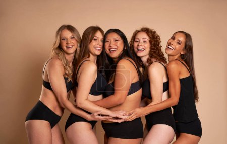 Téléchargez les photos : Groupe de femmes en sous-vêtements noirs collant et souriant vers la caméra - en image libre de droit