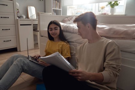 Photo for Two caucasian teenagers sitting on floor and learning from books and laptop - Royalty Free Image