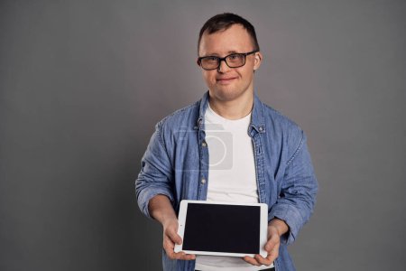 Foto de Hombre caucásico con síndrome de Down mostrando la pantalla en la tableta - Imagen libre de derechos