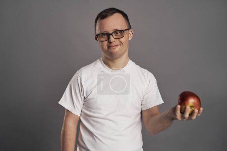 Foto de Hombre con síndrome de Down sosteniendo manos de manzana sobre fondo gris - Imagen libre de derechos
