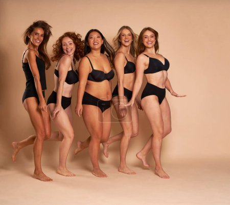 Photo for Group of cheerful women in black underwear standing and smiling towards the camera - Royalty Free Image