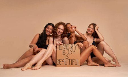 Foto de Grupo de mujeres en ropa interior sentadas en el suelo y sosteniendo la pancarta - Imagen libre de derechos