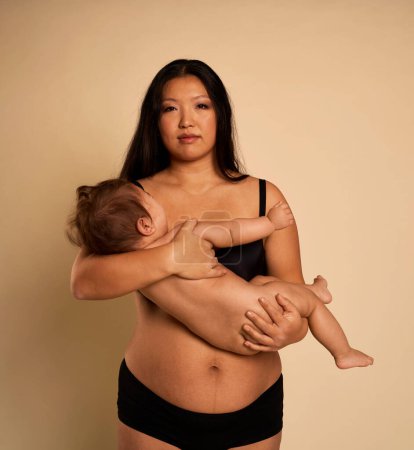 Photo for Portrait of Asian woman in underwear carrying a toddler - Royalty Free Image