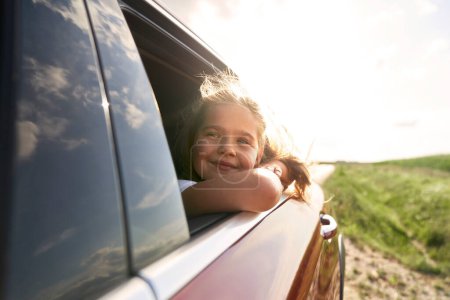 Photo for Caucasian girl of 8 years looking out of the car window while car trip - Royalty Free Image