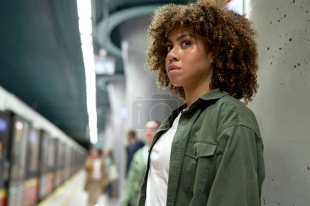 Foto de Joven afro mujer de pie en la plataforma y esperando el metro - Imagen libre de derechos
