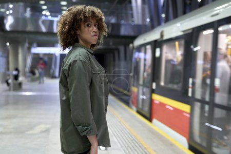 Foto de Joven afro mujer de pie en la plataforma y esperando el metro - Imagen libre de derechos
