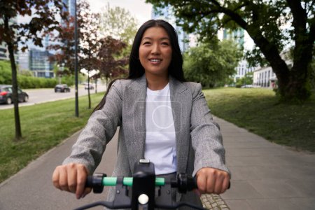 Foto de Vista frontal de la mujer china montando en scooter eléctrico en traje de negocios - Imagen libre de derechos