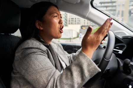 Foto de Mujer china frustrada gritando mientras conduce un coche - Imagen libre de derechos