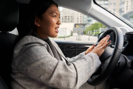 Photo for Side view of frustrated Chinese woman using car horn - Royalty Free Image