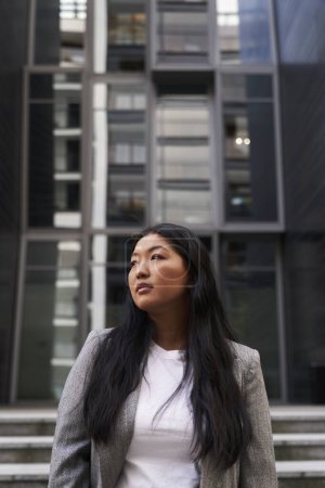 Téléchargez les photos : Femme chinoise d'affaires debout dans la rue avec un bâtiment sur le fond - en image libre de droit