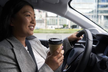 Téléchargez les photos : Femme chinoise conduisant une voiture et tenant une tasse de café - en image libre de droit