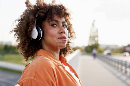 Foto de Joven mujer negra con auriculares y mirando hacia otro lado - Imagen libre de derechos
