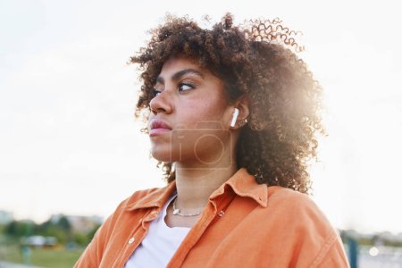 Photo for Close up of Black woman wearing earphones and looking away - Royalty Free Image