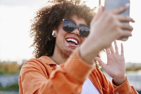 Foto de Mujer negra con gafas de sol y mirando su teléfono móvil - Imagen libre de derechos
