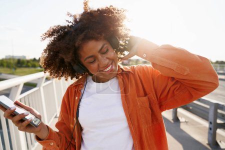 Foto de Mujer negra con auriculares y bailando en el puente - Imagen libre de derechos