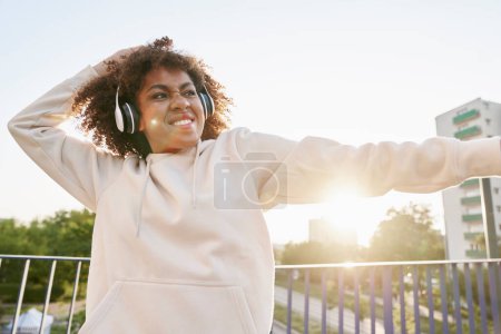 Téléchargez les photos : Femme noire portant des écouteurs et dansant sur le pont - en image libre de droit