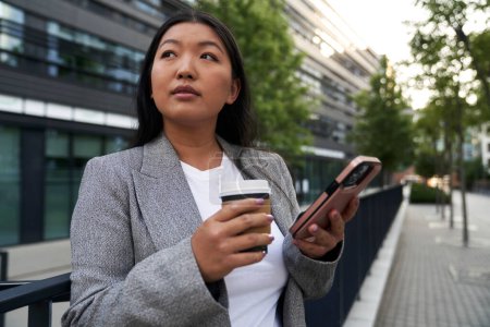 Téléchargez les photos : Femme chinoise d'affaires ayant un appel vidéo à côté du bâtiment - en image libre de droit