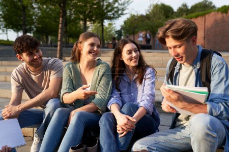 Téléchargez les photos : Groupe d'étudiants caucasiens assis à l'extérieur du campus universitaire - en image libre de droit