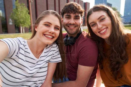 Téléchargez les photos : Portrait de trois étudiants universitaires caucasiens assis à l'extérieur du campus universitaire - en image libre de droit