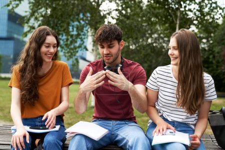 Téléchargez les photos : Groupe d'étudiants caucasiens assis à l'extérieur du campus universitaire et étudiant ensemble - en image libre de droit