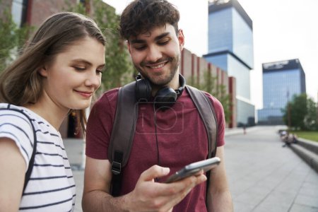 Téléchargez les photos : Deux étudiants qui naviguent au téléphone à côté du campus universitaire - en image libre de droit