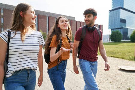 Téléchargez les photos : Groupe de trois étudiants caucasiens traversant le campus universitaire - en image libre de droit