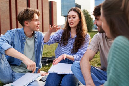 Photo for Group of caucasian students sitting outside the university campus and studying together - Royalty Free Image
