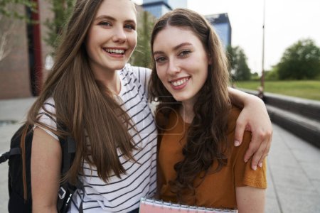 Photo for Portrait of two female caucasian university students sitting outside the university campus - Royalty Free Image