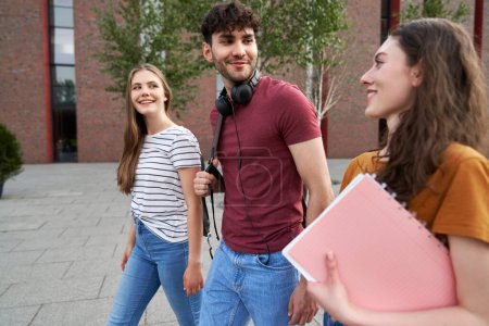 Téléchargez les photos : Groupe de trois étudiants caucasiens traversant le campus universitaire - en image libre de droit