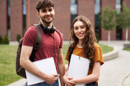 Portrait of two caucasian university students standing outside the university campus 