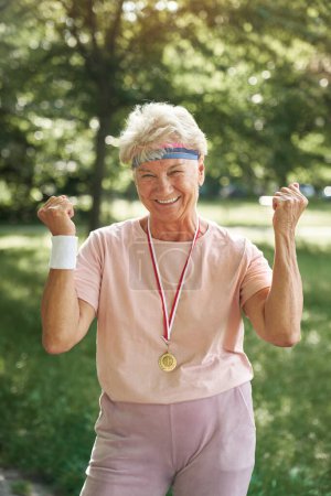 Téléchargez les photos : Portrait de femme âgée célébrant la victoire avec une médaille d'or - en image libre de droit