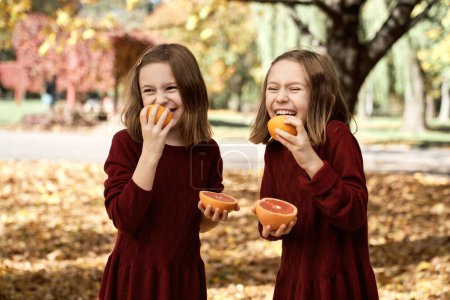 Photo for Child siblings standing in the woods and having fun while eating citrus fruits - Royalty Free Image