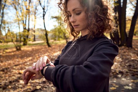 Téléchargez les photos : Femme caucasienne utilisant montre pendant faire du sport dans le parc - en image libre de droit