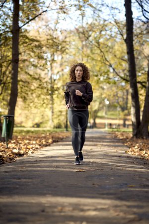 Téléchargez les photos : Gros plan de femme caucasienne sautant dans le parc à l'automne avec les bras tendus - en image libre de droit