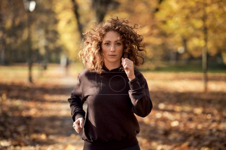 Téléchargez les photos : Pensive femme caucasienne jogging dans le parc à l'automne - en image libre de droit