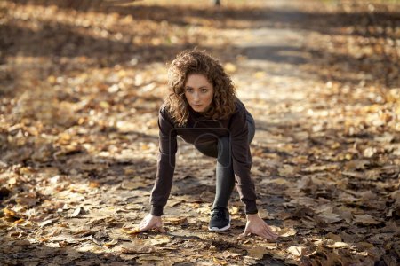Téléchargez les photos : Femme caucasienne sur le point de commencer à courir dans le parc à l'automne - en image libre de droit