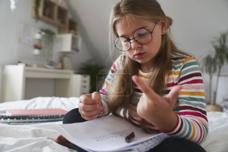 Photo for Focus elementary age girl studying maths at the bed - Royalty Free Image