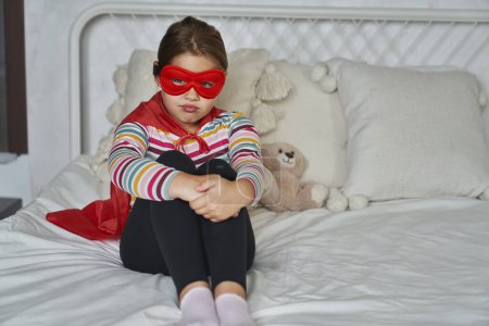 Téléchargez les photos : Fille caucasienne portant costume de super-héros et assis avec tristesse - en image libre de droit