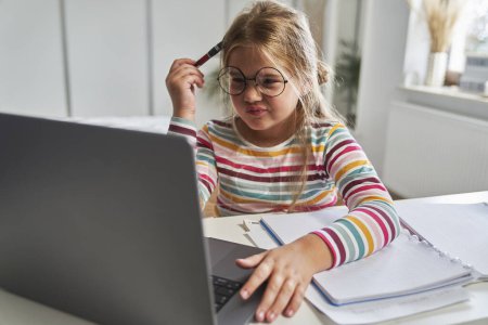 Photo for Caucasian elementary age girl studying on laptop and having problems with understanding - Royalty Free Image
