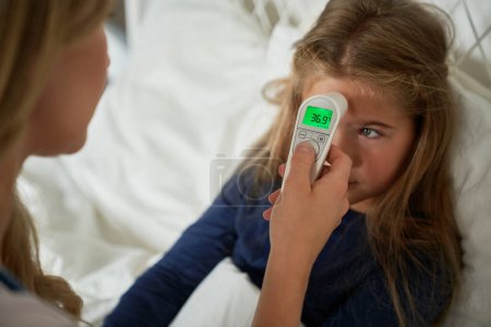 Téléchargez les photos : Mère vérifiant la température avec thermomètre de la petite fille - en image libre de droit