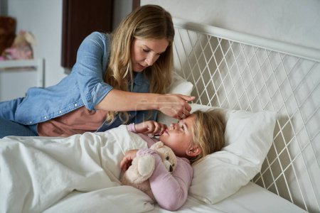 Foto de Madre cuidando a su hija enferma en casa - Imagen libre de derechos