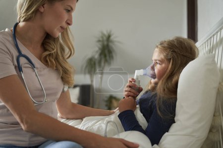 Photo for Doctor giving  nebulizer to an ill child at home - Royalty Free Image
