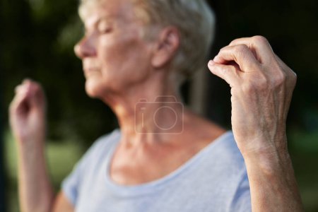 Foto de Mujer mayor tranquila meditando en el parque junto al lago - Imagen libre de derechos