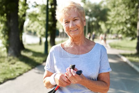 Foto de Retrato de una mujer mayor sosteniendo bastones nórdicos en el parque - Imagen libre de derechos