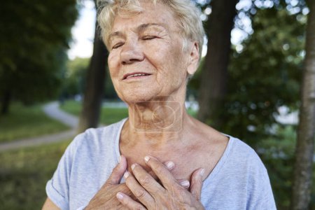 Téléchargez les photos : Femme âgée calme faisant de l'exercice respiratoire dans le parc - en image libre de droit