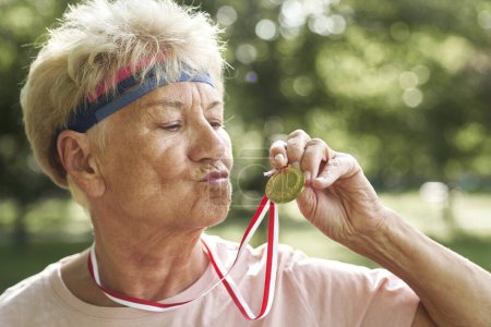 Téléchargez les photos : Femme senior célébrant la victoire avec une médaille d'or - en image libre de droit